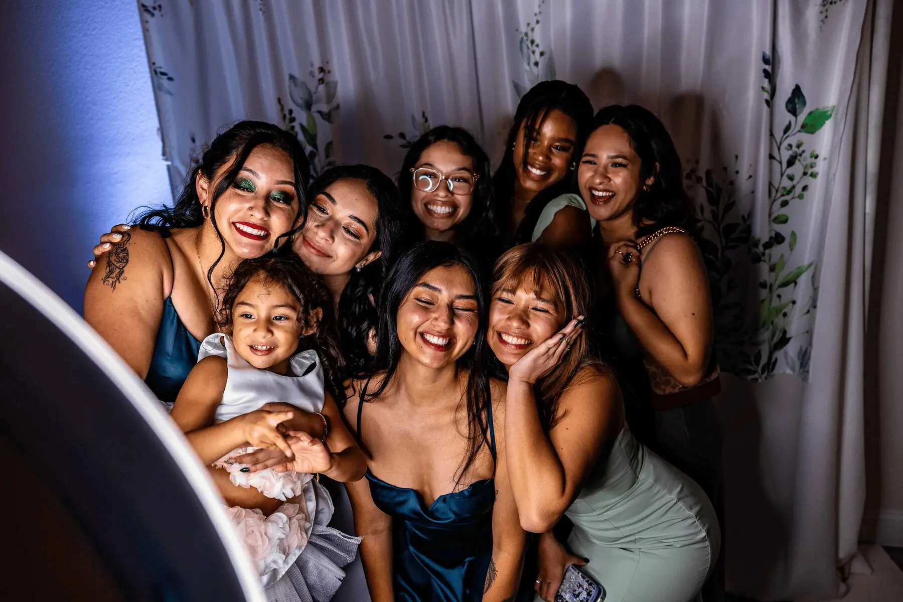 Wedding reception guests laughing with props in the open-air booth